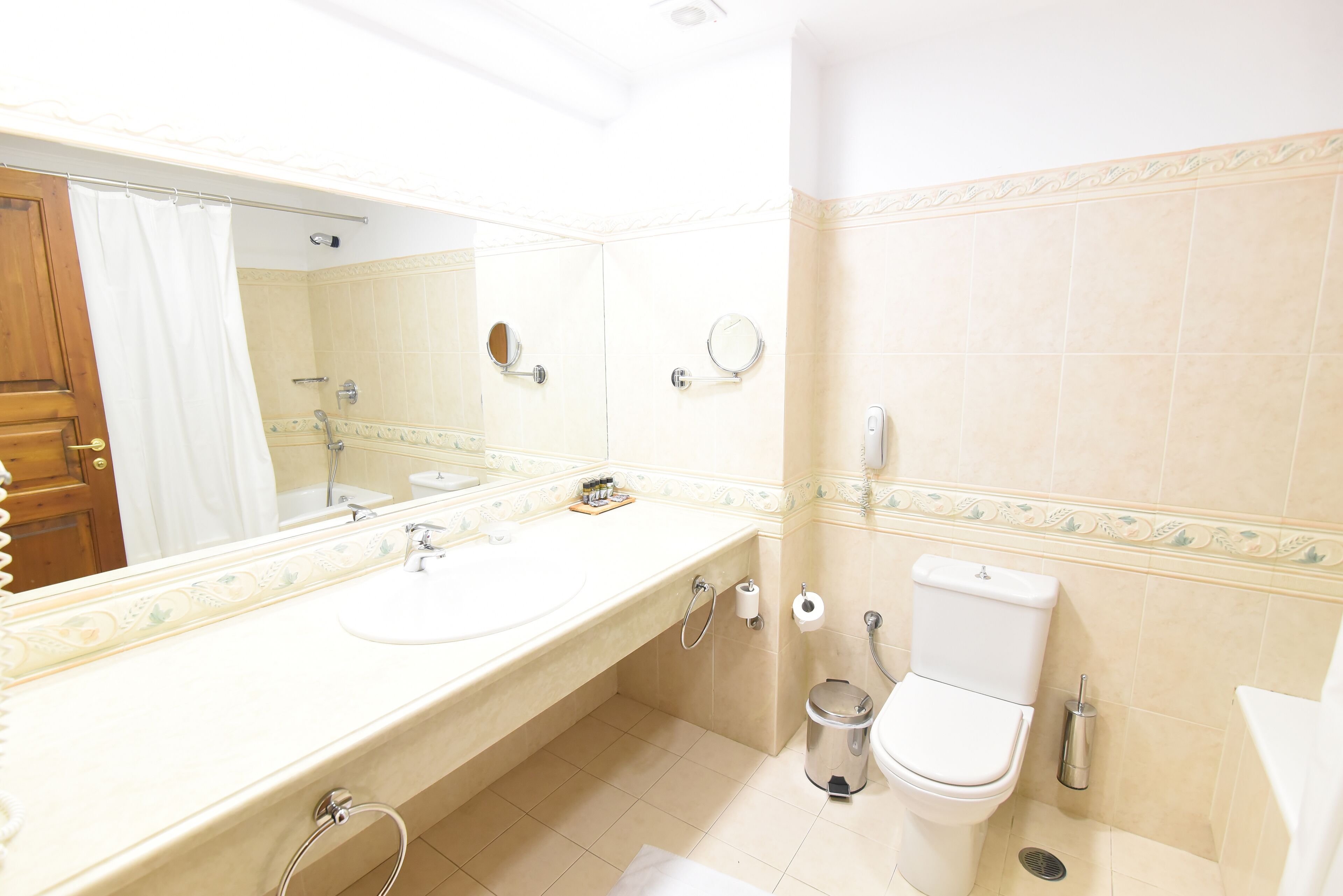 A bathroom with a sink, mirror, toilet, and shower.