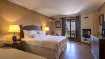 A hotel room with two beds, a TV, a fireplace, and a balcony with curtains.