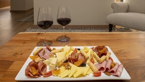 Ein gemütliches Wohnzimmer mit einem Holztisch, auf dem eine Wurstplatte, zwei Gläser Rotwein und ein Flachbildfernseher über einem Kamin angebracht sind.