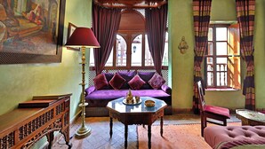 A room with a sofa, a table with a tray, a lamp, and a chair.