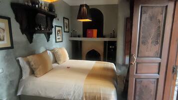 A bedroom with a bed, a fireplace, and a door.