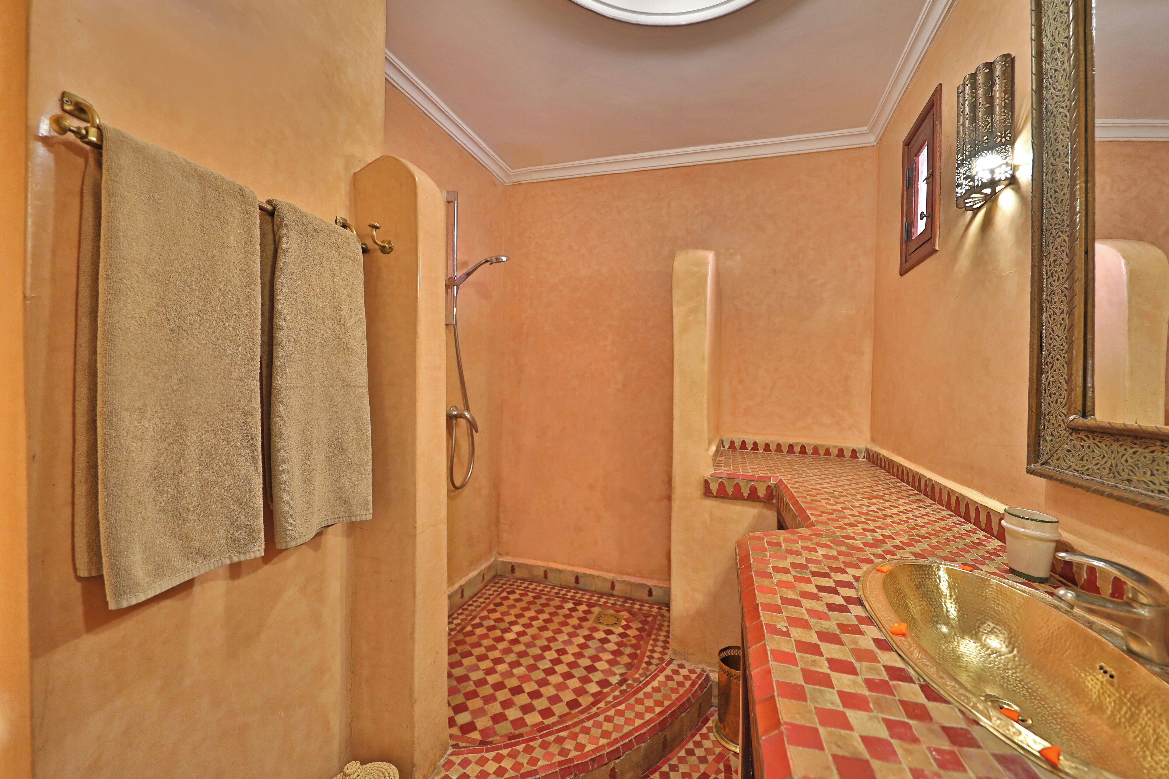 A bathroom with a checkered floor, a sink with a basin, and two towels hanging on the wall.