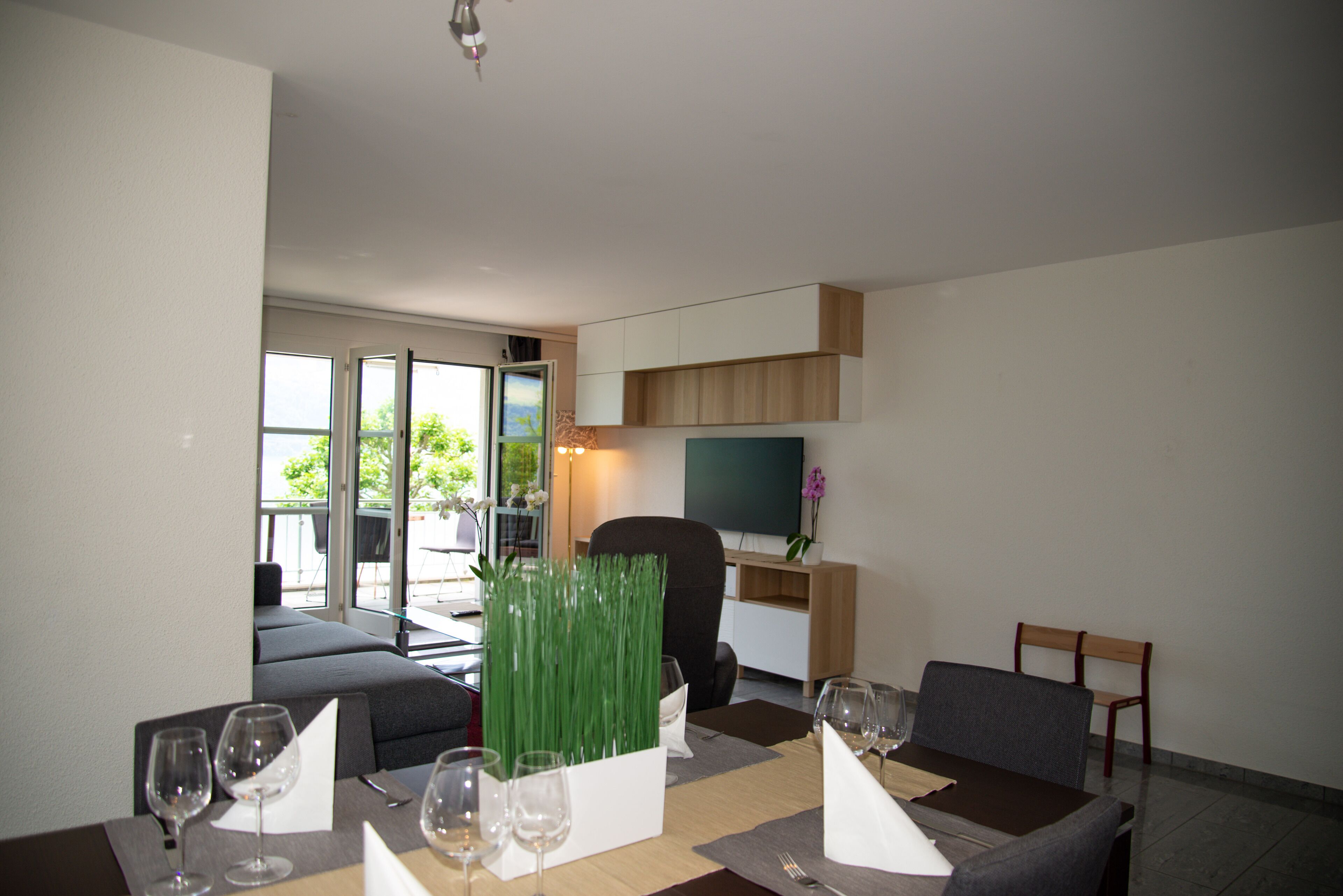 A modern dining area with a table set for four, a sofa, and a view of the outdoors.