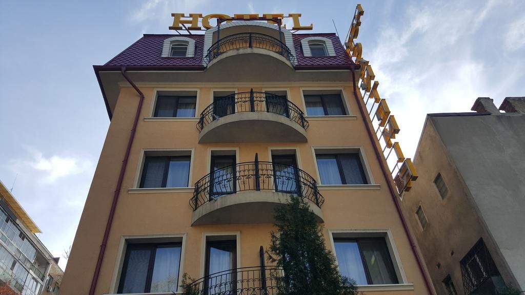A hotel building with a prominent 'HOTEL' sign on the roof, multiple balconies, and a clear sky.