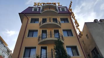 A hotel building with a prominent 'HOTEL' sign on the roof, multiple balconies, and a clear sky.