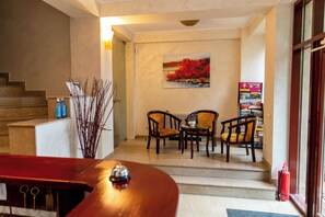A hotel lobby with a staircase, a reception desk, a painting, and a seating area with chairs. - Cantemir (Bucharest)