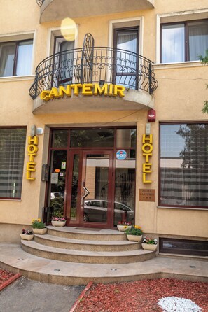 A hotel entrance with a balcony, a sign reading 'CANTEMIR HOTEL', and a car parked in front. - Cantemir (Bucharest)