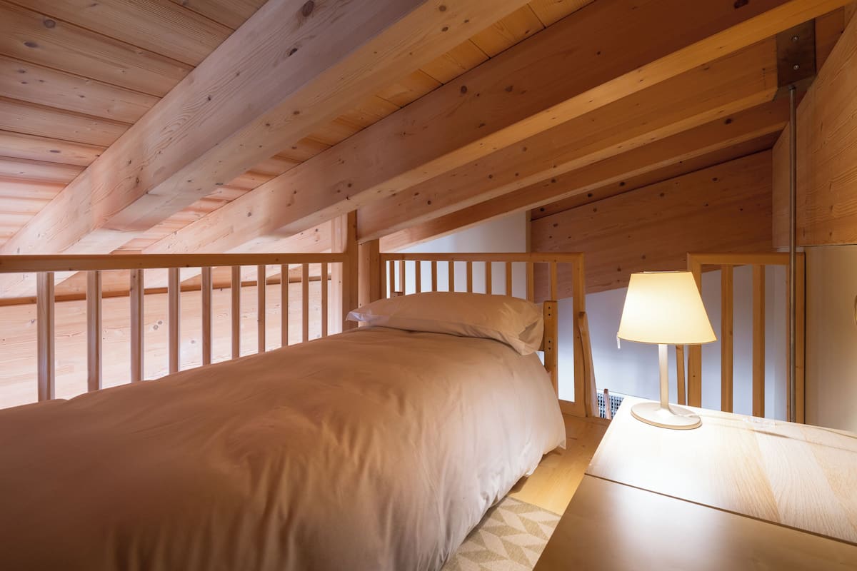 A wooden ceiling with a bed and a nightstand with a lamp.