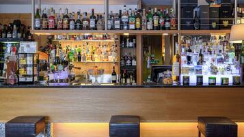 Un bar con numerose bottiglie di liquori, un bancone in legno e due sgabelli.
