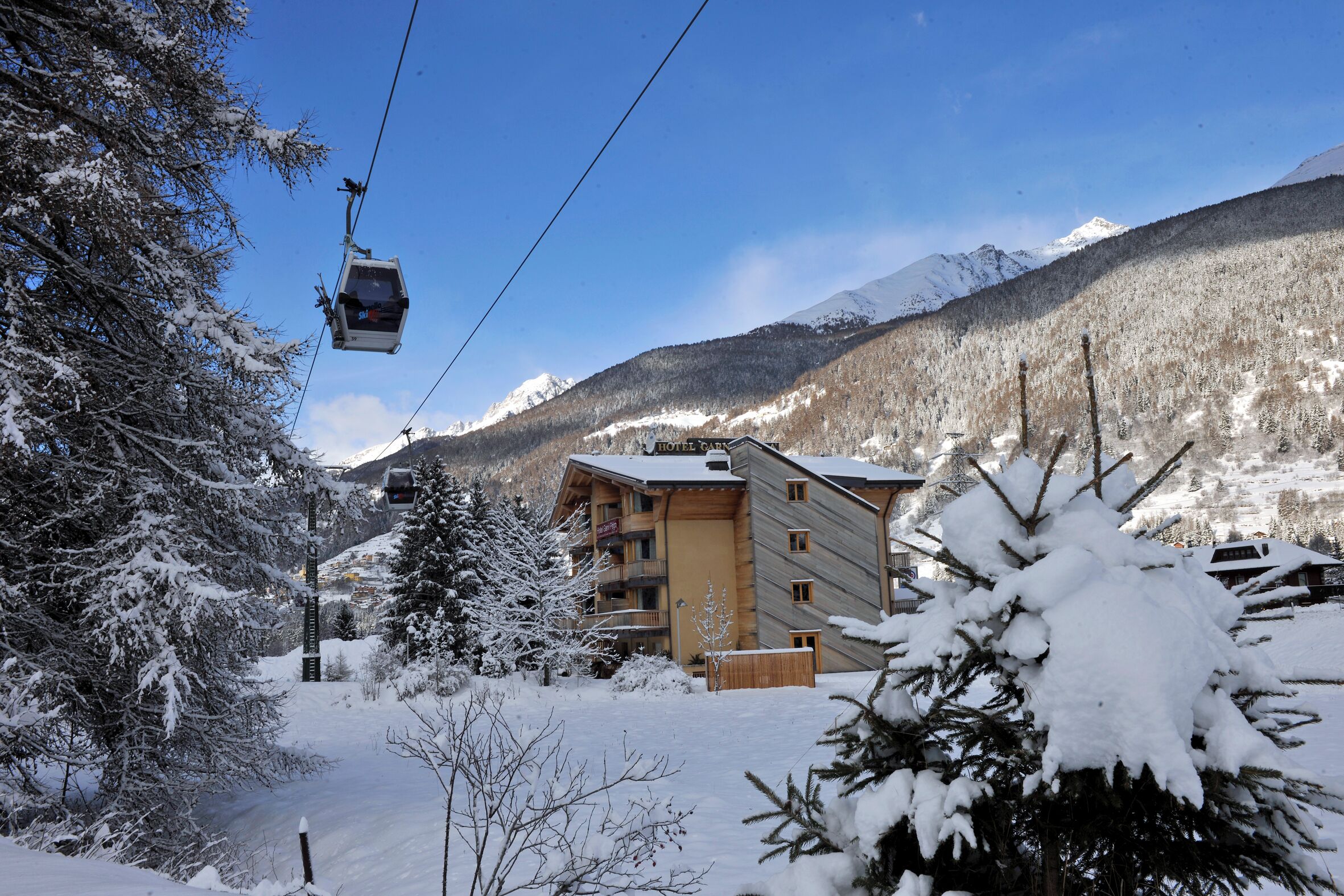 A snow-covered mountain area with a ski lift, a lodge, and a view of snow-capped mountains.