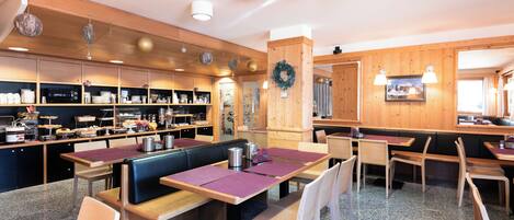 A restaurant with booths and tables, wooden decor, and a kitchen area.