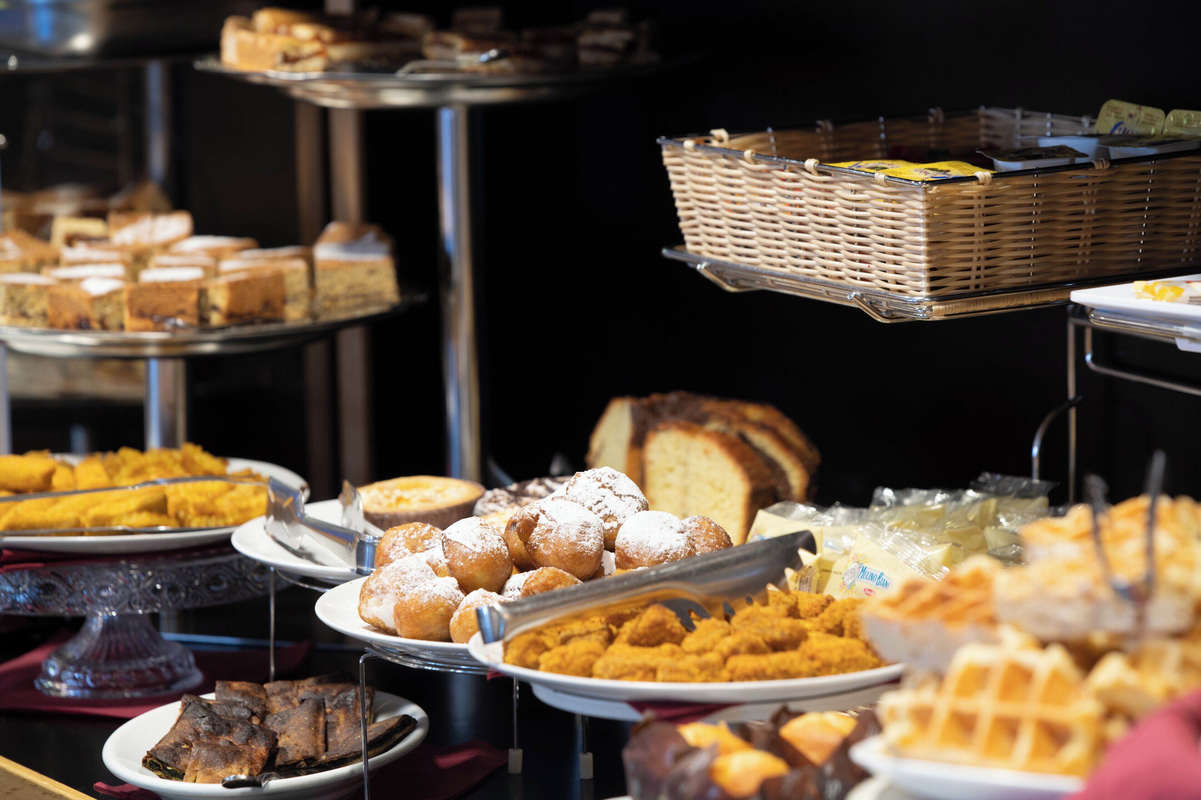 Un buffet con diversi cibi tra cui pasticcini, pane e waffle.