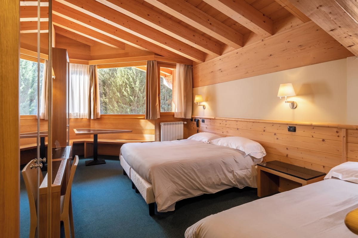 A wooden cabin room with two beds, a table, and a bench.