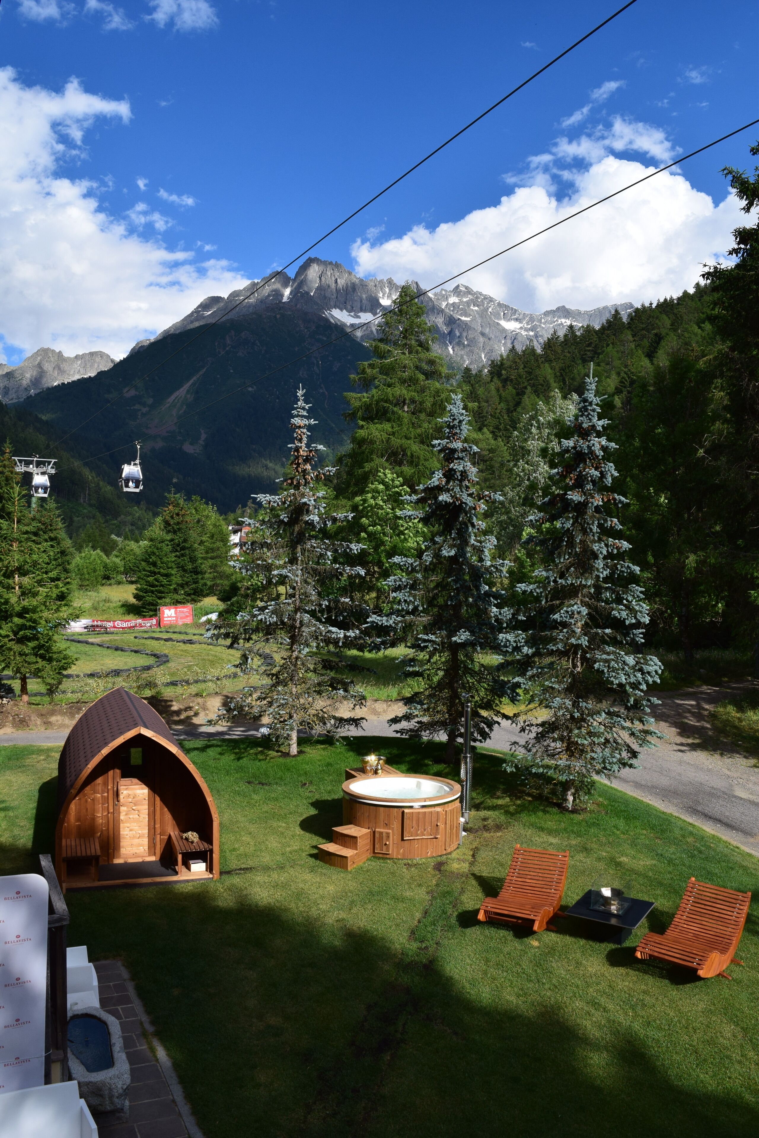 A mountain lodge with a hot tub, lounge chairs, and a wooden cabin.