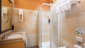 Un baño moderno con cabina de ducha de vidrio, un lavabo y un espejo.