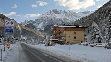 A hotel with a mountain backdrop, a sign for a bar, and a sign for a 24-hour service.