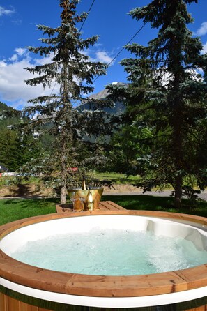 A hot tub surrounded by trees and a mountain backdrop. - Hotel Garnì Pegrà (Ponte di Legno)
