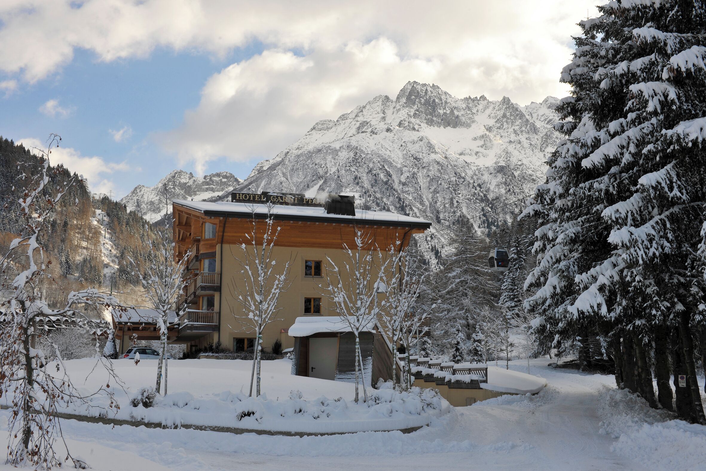 A hotel with a mountain backdrop, wooden exterior, and snow-covered surroundings.