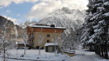 A hotel with a mountain backdrop, wooden exterior, and snow-covered surroundings.