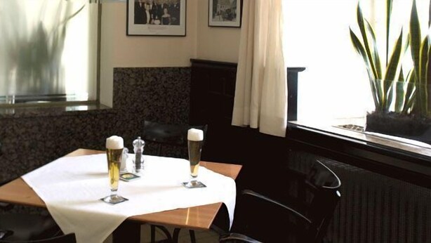 A dining table with two glasses of beer, a salt and pepper shaker, and a framed picture on the wall. - Hotel Csejtei (Feldbach)