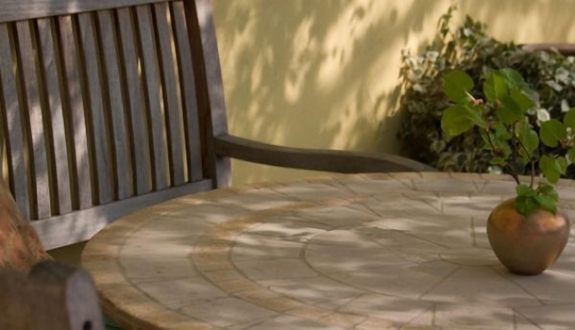 A round stone table with a potted plant.