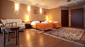 Habitación de hotel con dos camas, un sofá, una mesa de madera y una alfombra estampada.