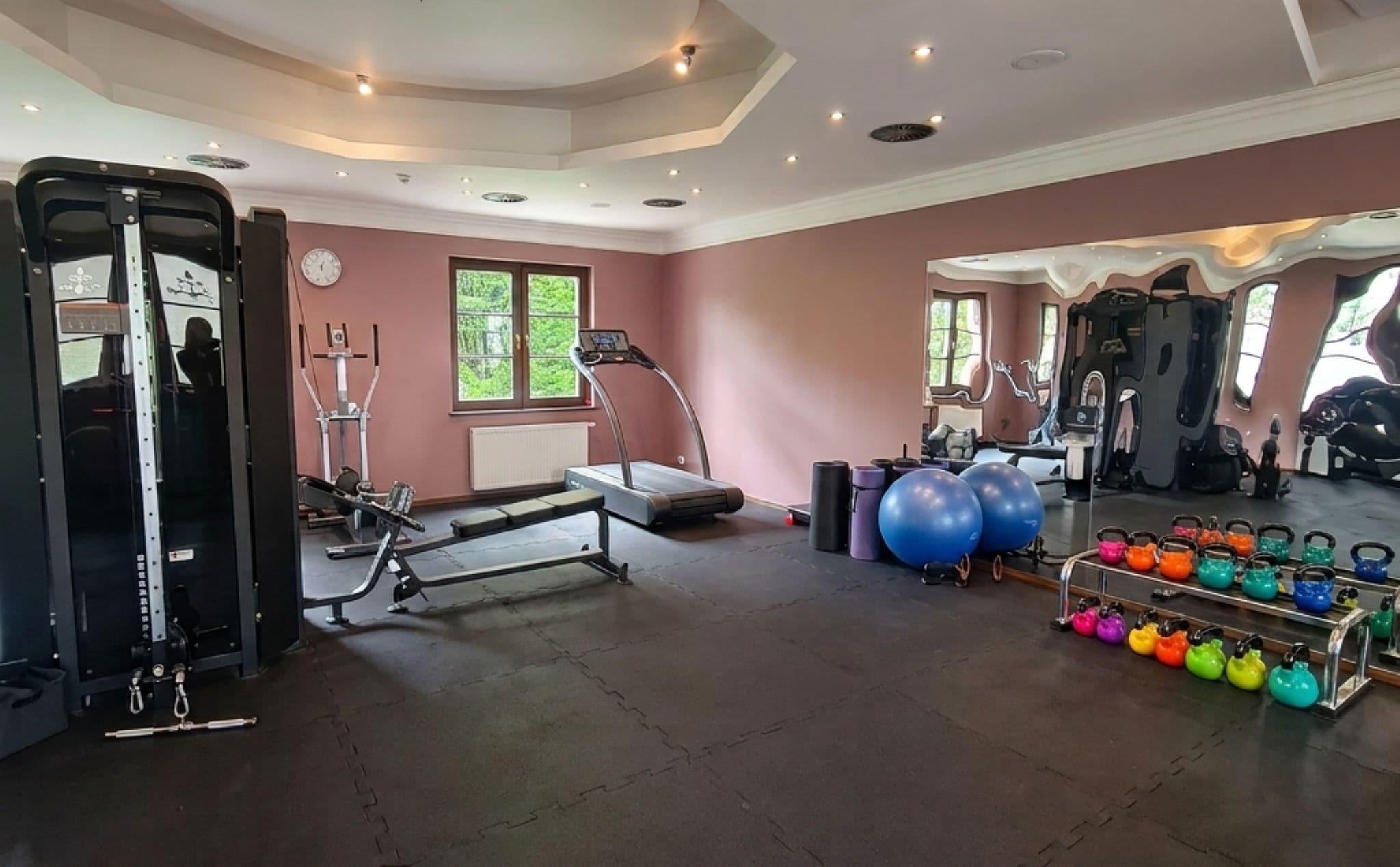 A gym with exercise equipment, treadmills, and kettlebells.