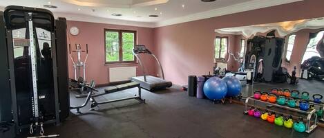 A gym with exercise equipment, treadmills, and kettlebells.