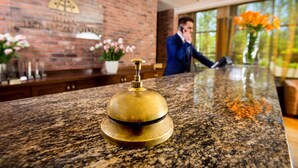 Un área de recepción con mostrador de granito, una campana de bronce y una pared de ladrillo con un emblema decorativo.
