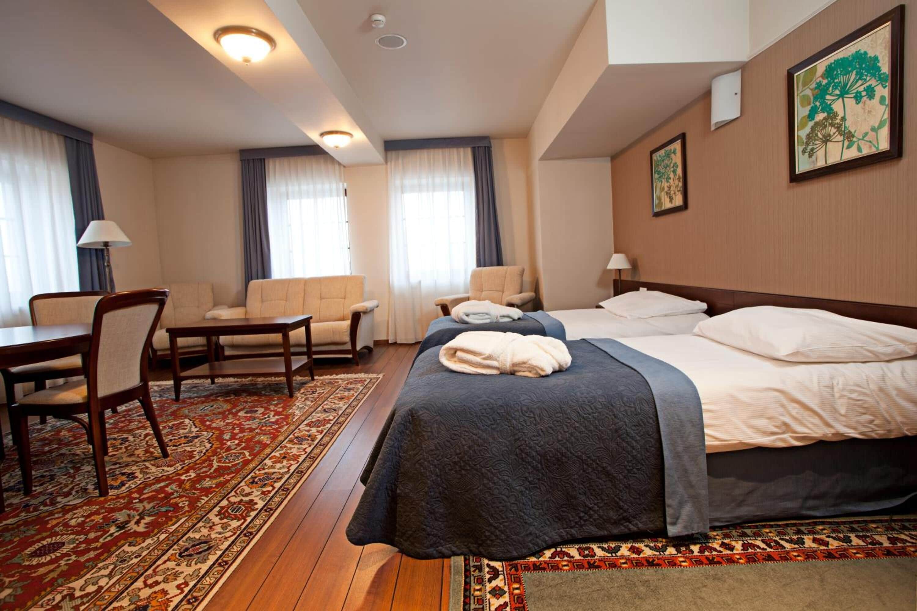 Una habitación de hotel con una cama grande, dos sillones, una mesita y un escritorio.