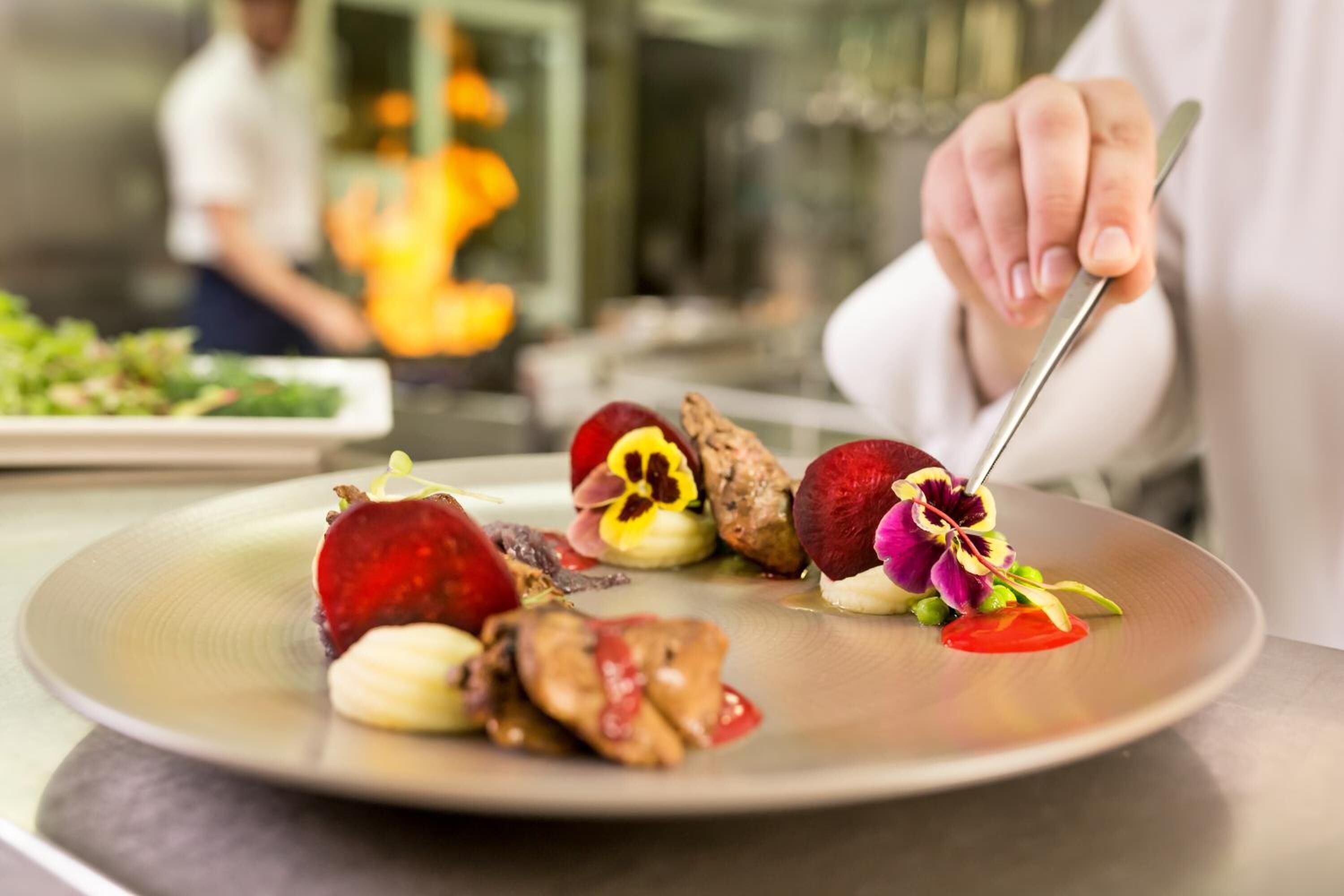 Un chef prépare un plat en utilisant une variété d’ingrédients qu’il dispose sur une assiette.