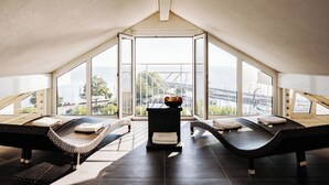 Una habitación con dos sillones reclinables, una mesita con un frutero, y vista a la ciudad a través de amplias ventanas.