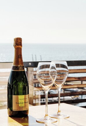 A bottle of champagne and two glasses on a wooden table with a view of the ocean. - Seehotel Litz (Langenargen)
