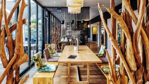 Un interior moderno con una mesa de comedor de madera, bancos y una lámpara colgante.