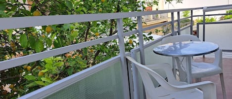 A balcony with a table and chairs, surrounded by a metal railing and a mesh screen.
