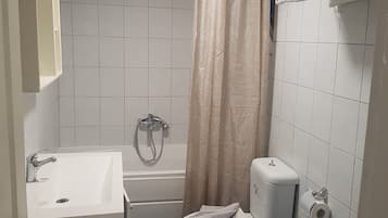 Een kleine badkamer met bad, toilet en wastafel.