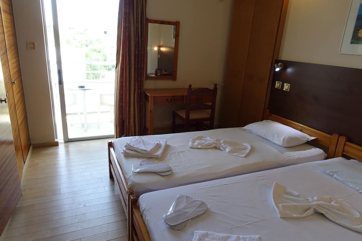 Habitación de hotel con dos camas, un escritorio de madera, una silla y un espejo grande.