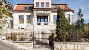 Um edifício de dois andares com uma entrada central e uma placa com o dizer 'VILLA PEATO'.
