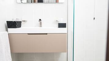 A bathroom with a white sink, beige cabinet, and patterned floor tiles.