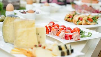 Una mesa de buffet con diversos alimentos, incluyendo queso, frutas y pasteles.