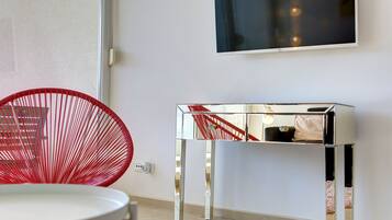 Relax in a spacious room with a large flat-screen TV, sleek side table, and stylish chair.