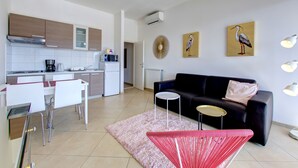 Un espacio habitable moderno con cocina, comedor y un sofá negro.