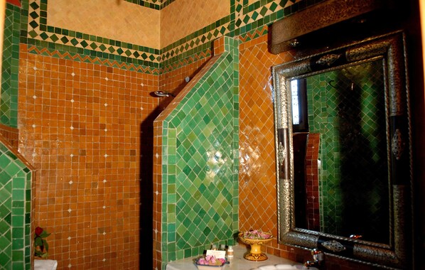 Un baño con paredes de mosaicos, un lavabo y un espejo.