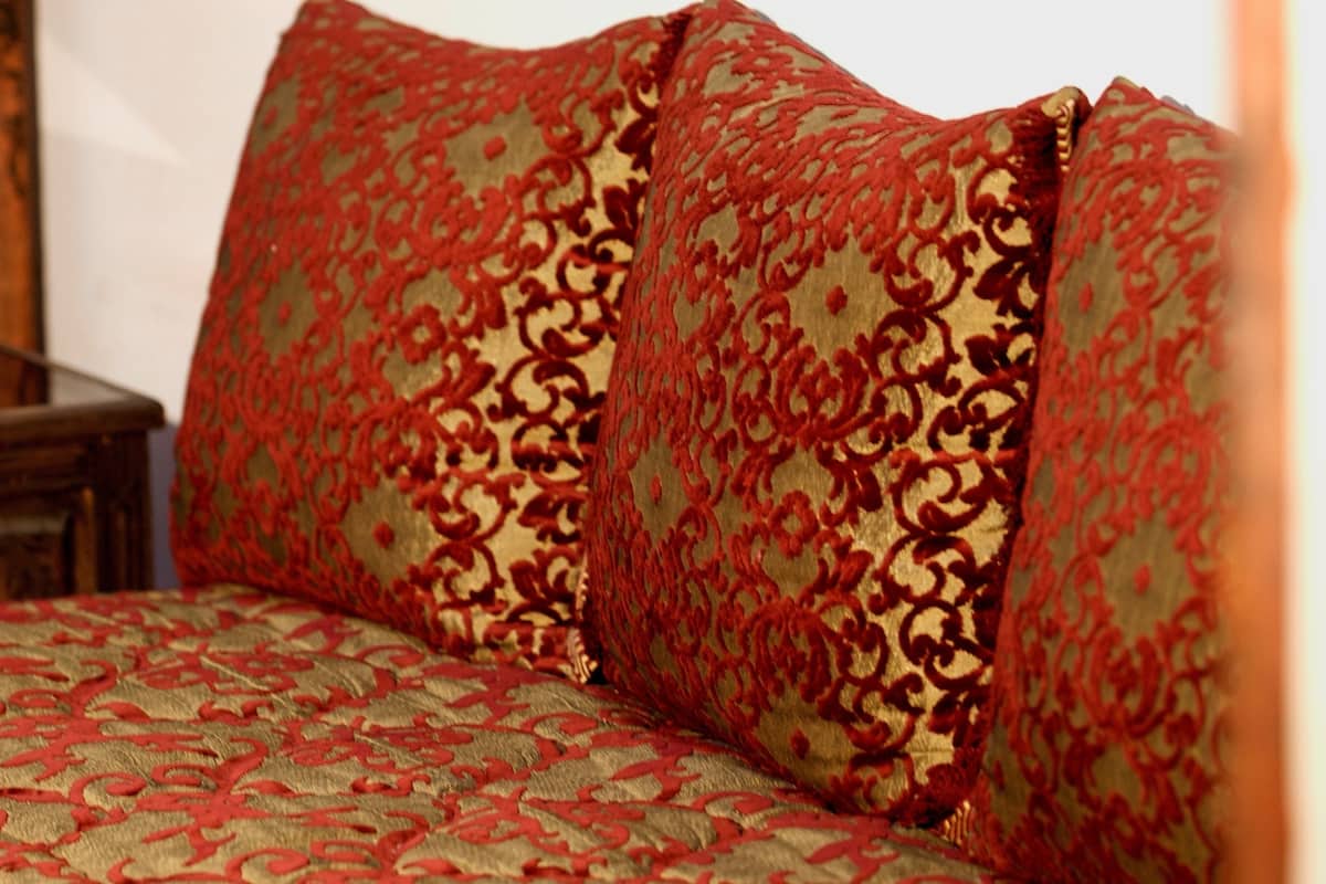A bed with a patterned bedspread and two decorative pillows.