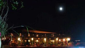 A building with a covered outdoor area, possibly a restaurant or bar, with lights and a pool in the foreground. - Dar Tazi - Medina View (Fes)