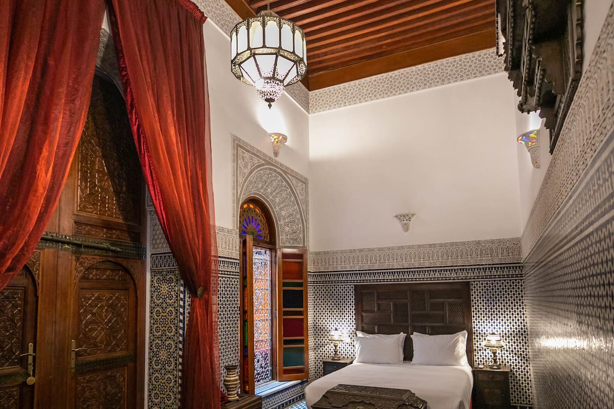 A traditional Moroccan room with a bed, sofa, and a coffee table.