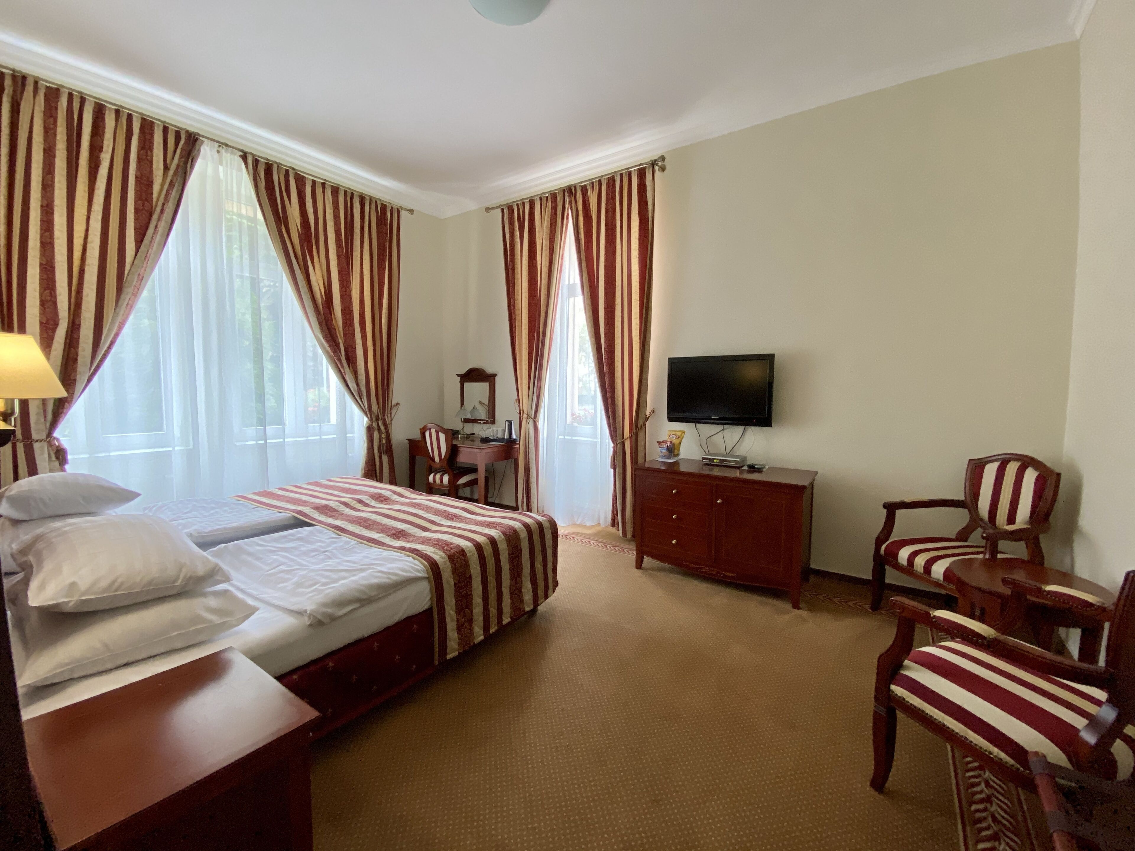 A hotel room with a bed, a desk, a television, and two chairs.