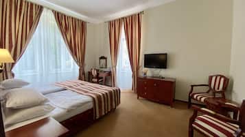 Una habitación de hotel con una cama, un escritorio, un televisor y dos sillas.