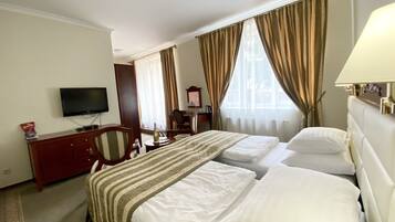 A hotel room with a bed, a TV, a desk, and a chair.