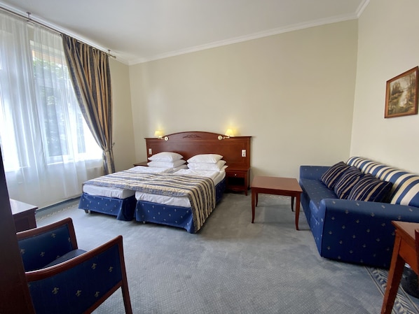A hotel room with a bed, a sofa, a chair, and a small table.